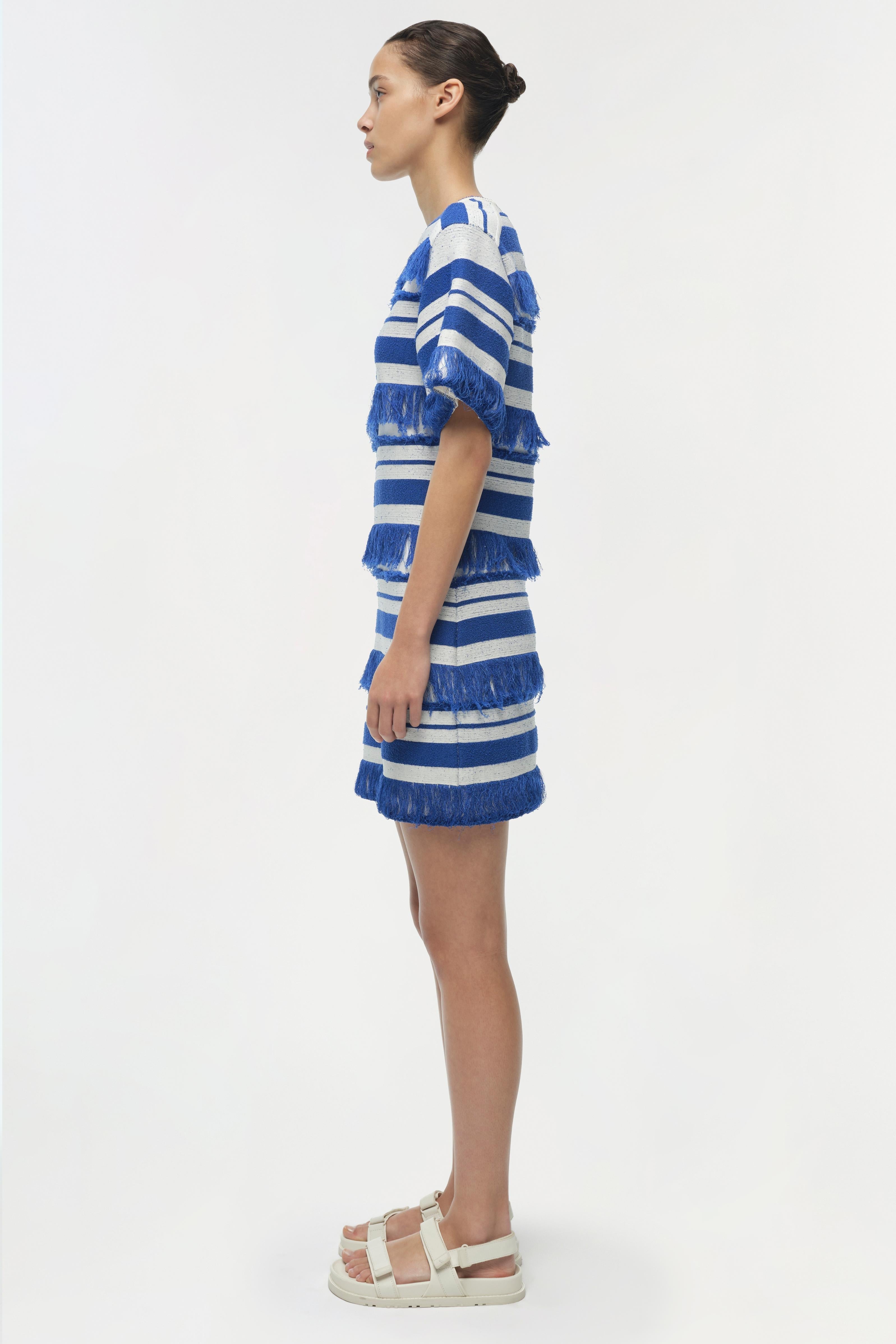 Blue and white striped knit mini dress with textured fringe trim on short sleeves and tiered skirt sections.