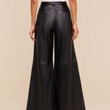 Wearing the Chelsy Leather Wide-Leg Pant in a high-rise, black lightweight leather, paired with a white sleeveless top, a person is pictured from the back against a plain beige background.