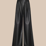 The Chelsy Leather Wide-Leg Pant is a high-waisted, wide-leg black leather pair displayed against a plain beige background. These pants feature a smooth texture and subtle seam detailing at the knee area.