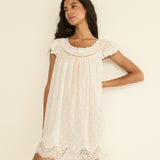 Woman wearing a white lace nightgown against a plain background