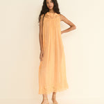 Woman wearing a peach-colored dress against a plain background