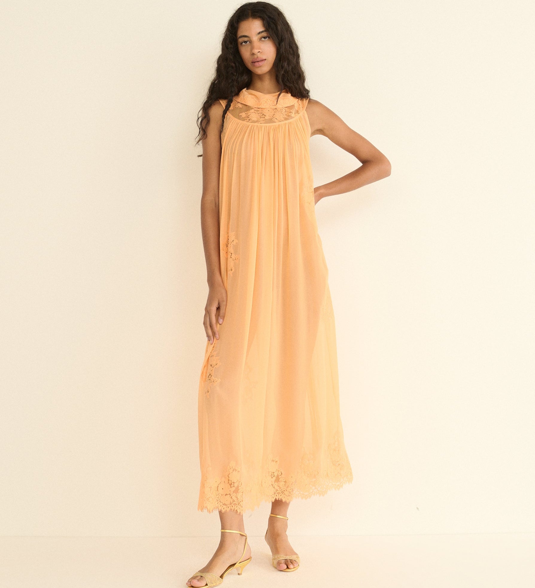 Woman wearing a peach-colored dress against a plain background