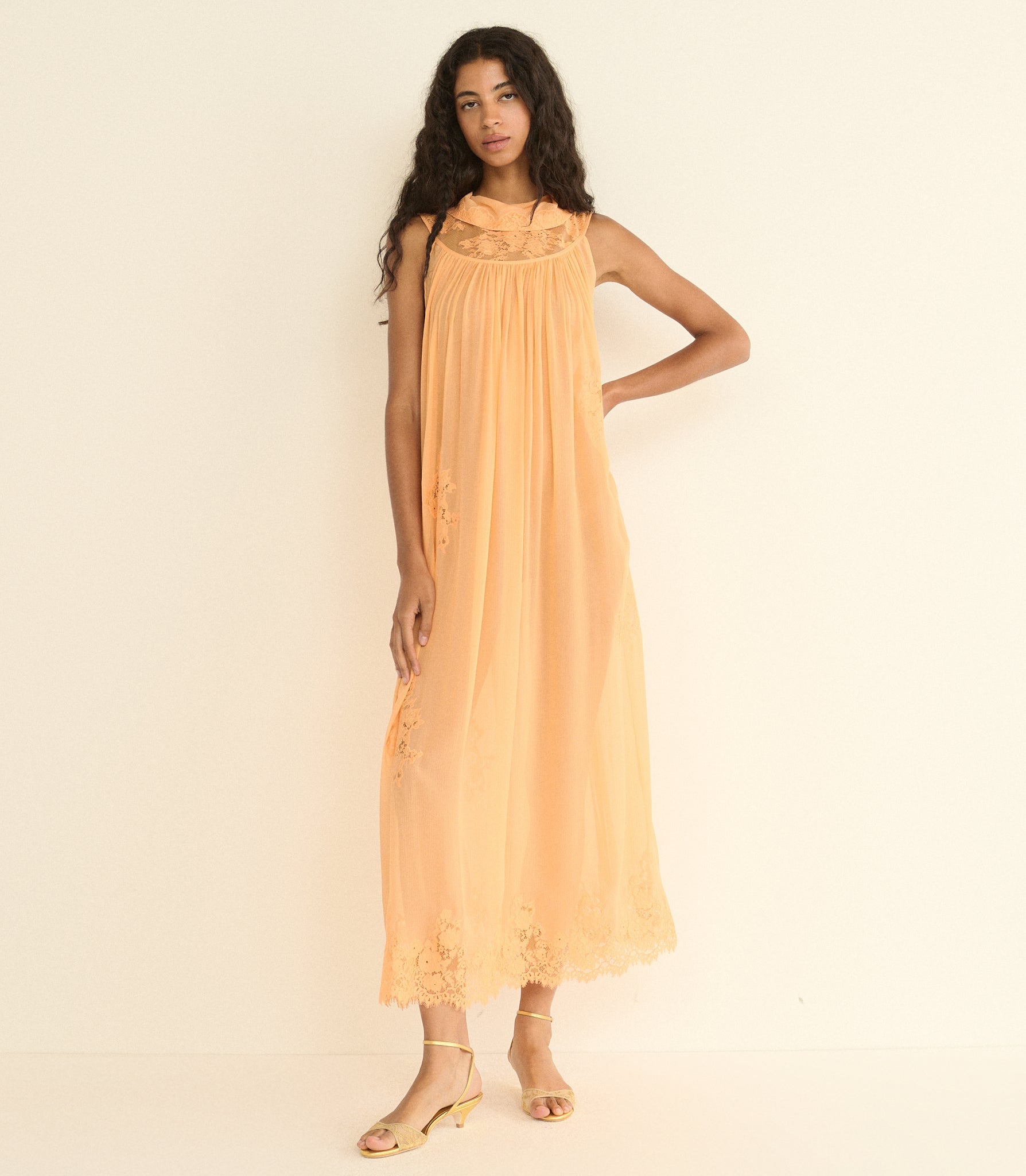 Woman wearing a peach-colored dress against a plain background