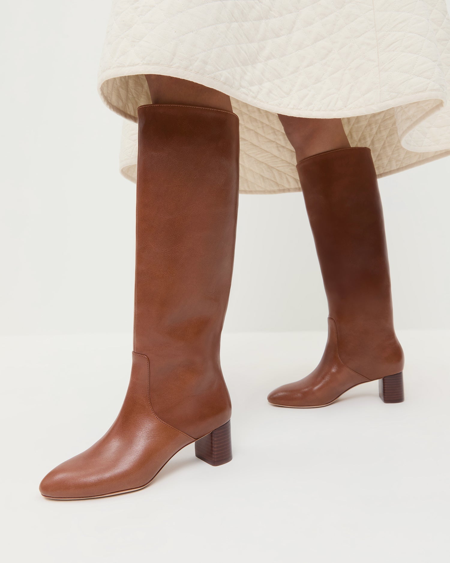 Gia Safari Leather Tall Boot in safari brown leather and Clara Quilted Skirt in cream.