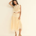 Woman wearing a light beige lace outfit against a plain background