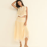 Woman wearing a light beige lace outfit against a plain background