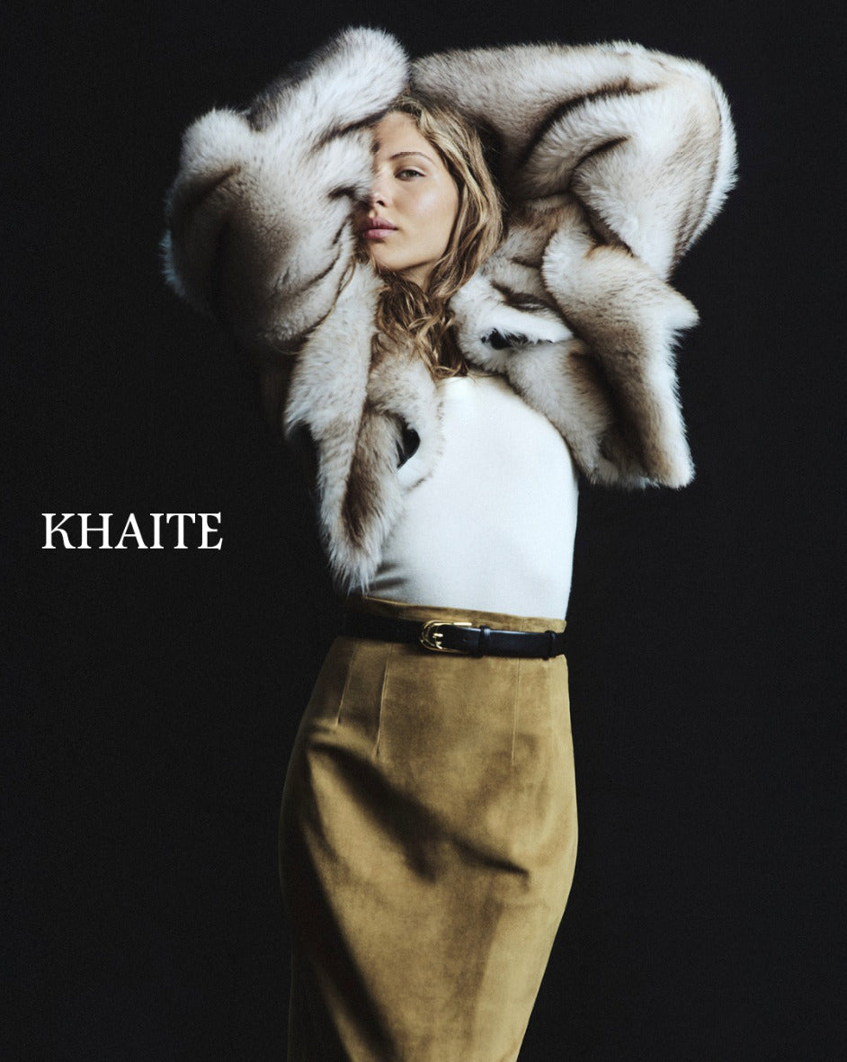 Person wearing a white fur coat over shoulders with 'Khaite' branding on a black background