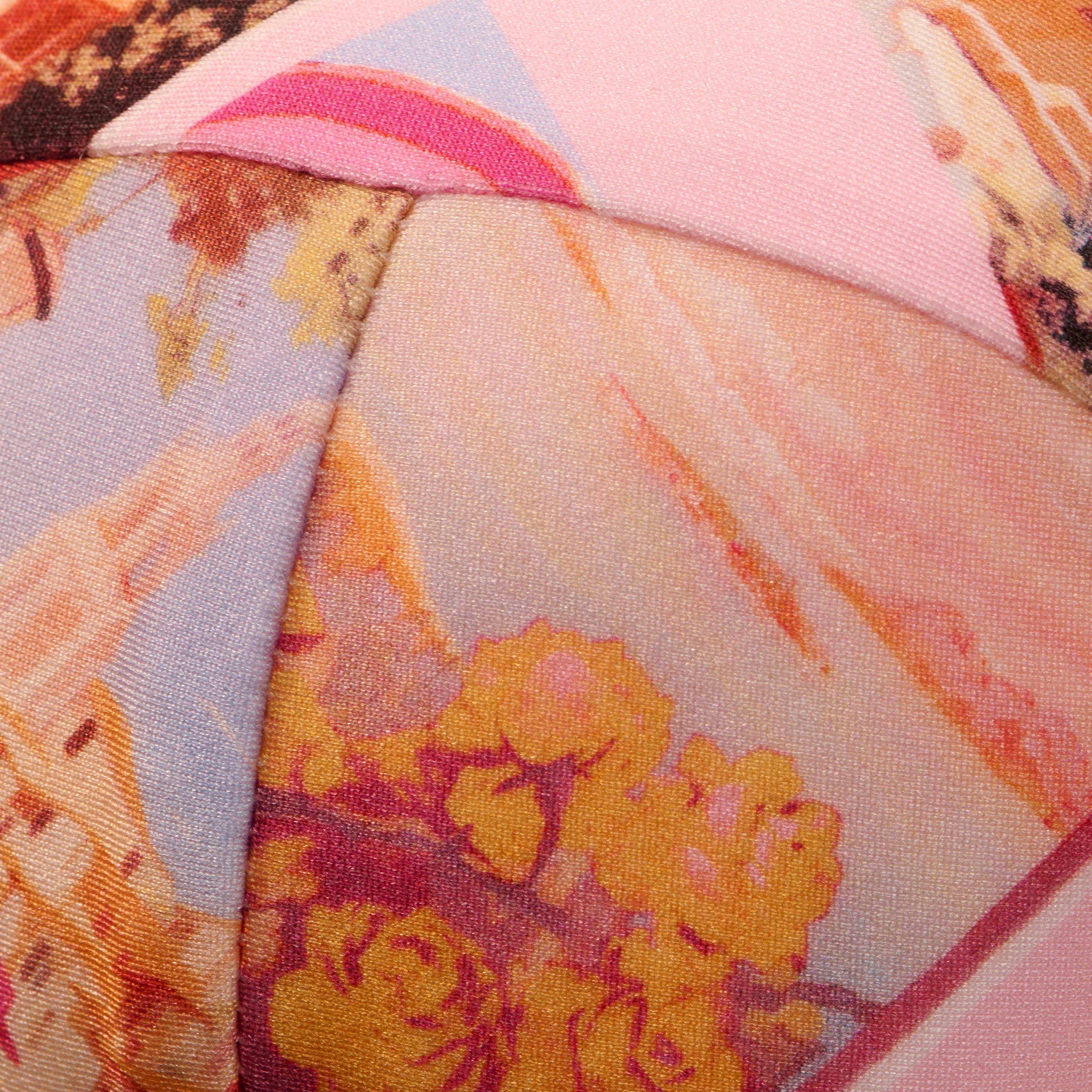 Close-up of the Alexandria Bikini Tops fabric, featuring a colorful abstract floral and postcard print in pink, yellow, orange, and blue with curved, overlapping stitching. Offers UPF 50 protection for stylish sun safety.