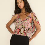Woman wearing a floral top against a plain background