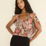 Woman wearing a floral top against a plain background