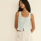 Woman wearing a light blue floral sleeveless top against a beige background