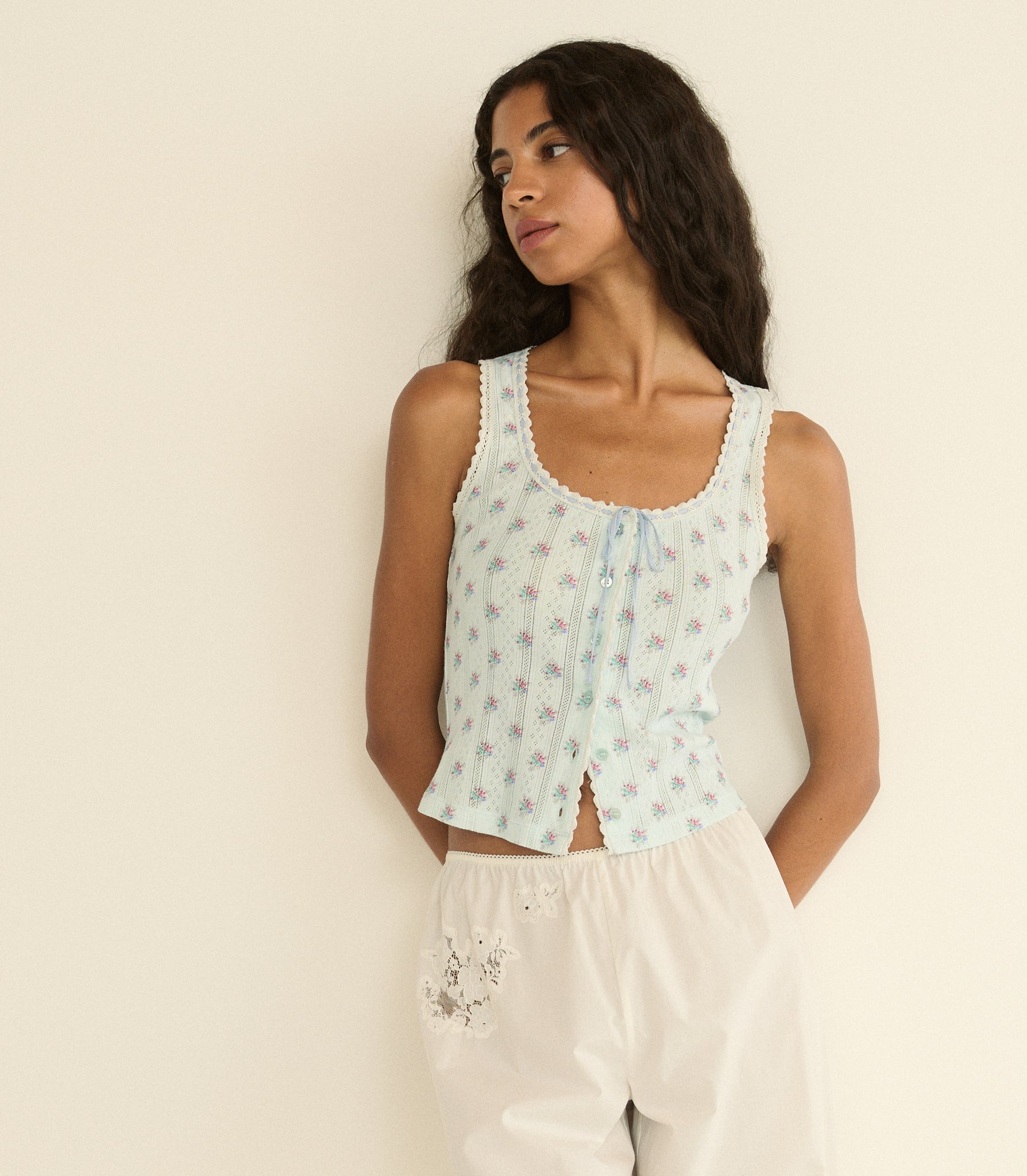 Woman wearing a light blue floral sleeveless top against a beige background