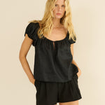 Woman wearing a black top and shorts set on a beige background