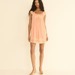 Woman wearing a peach dress against a beige background