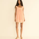Woman wearing a peach dress against a beige background