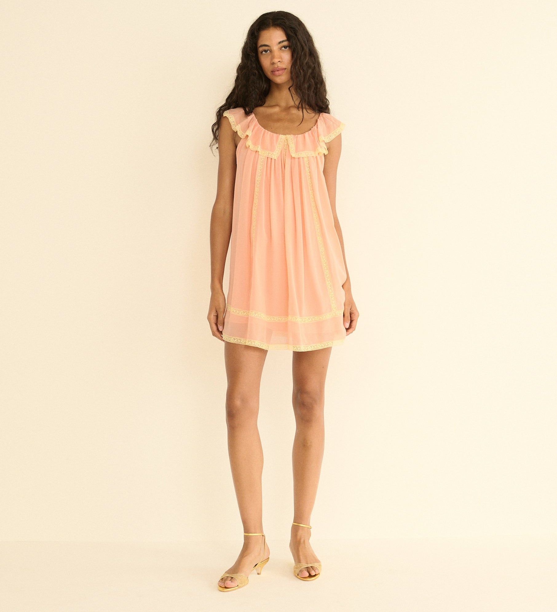 Woman wearing a peach dress against a beige background