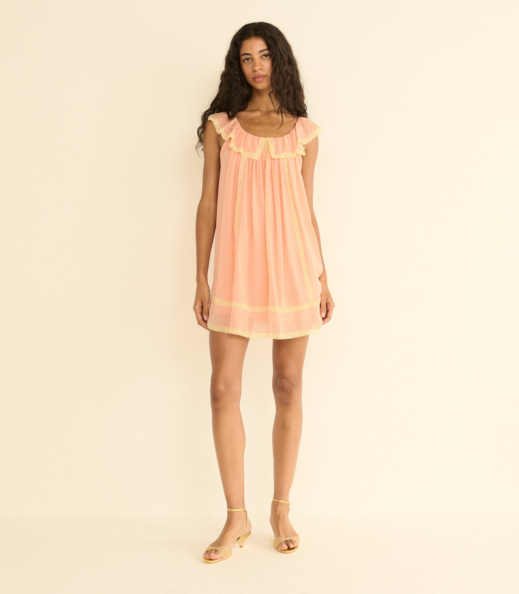Woman wearing a peach dress against a beige background