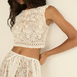 Woman wearing a white lace top and skirt against a plain background