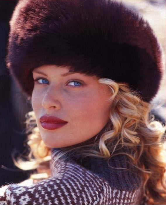 Woman wearing a fur hat and patterned sweater with a blurred background