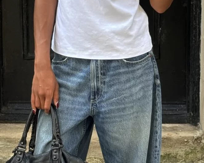 woman standing outside holding an it bag in 2000s fashion look