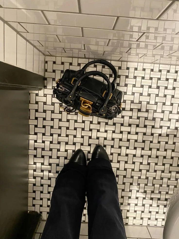 Black Paddington bag on patterned tiles beside black shoes.